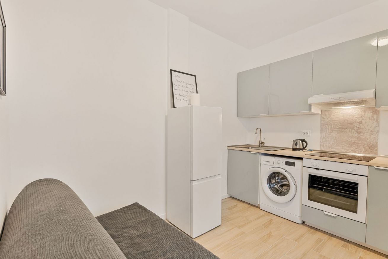 A compact kitchen with a washing machine, oven, and a refrigerator.