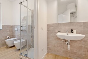 Ein modernes Badezimmer mit Duschkabine aus Glas, einem weißen Waschbecken und einer Toilette.