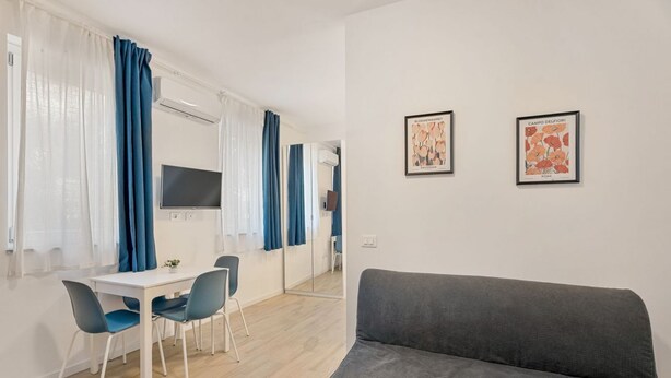 A modern living room with a grey sofa, a dining area with a white table and blue chairs, and two framed artworks on the wall. - [Il Parco Apartment 6] Natura & Relax-RoadTo5Terre (Beverino)