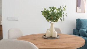 Un tavolo rotondo in legno con una pianta in vaso e tre vasi bianchi.