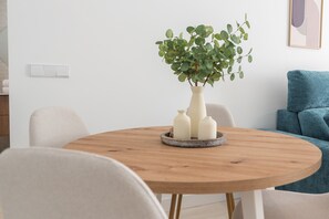 Ein runder Holztisch mit einem Blumentopf und drei weißen Vasen.