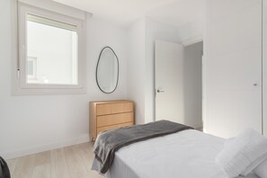 A bedroom with a bed, a dresser, a mirror, and a door. - Apartamentos Puerto by H - Centro Ayamonte AEHP12CP104 (Ayamonte)