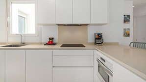 Una cucina moderna con mobili bianchi, forno integrato e macchina per il caffè.