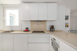 Eine moderne Küche mit weißen Schränken, einem eingebauten Ofen und einer Kaffeemaschine.