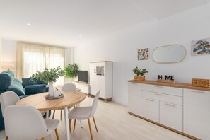 Un salon moderne comprenant un coin repas, un canapé, un téléviseur et un meuble agrémenté d’objets décoratifs.