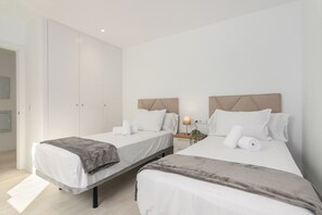 Une chambre d’hôtel avec deux lits, une table de chevet avec une lampe et une armoire.