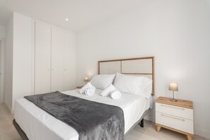 Et soveværelse med en seng, to sengeborde, et skab og en lampe.