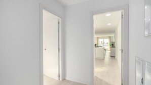 Un corridoio che conduce a una cucina con pareti bianche e pavimento in legno.