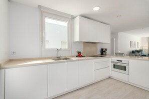 A modern kitchen with white cabinetry, a stainless steel sink, and a built-in oven. - Apartamentos Puerto by H - Centro Ayamonte AEHP12CP104 (Ayamonte)