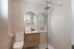 Une salle de bain moderne équipée de toilettes, d’un lavabo et d’une douche.