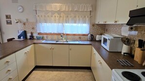 A kitchen with a sink, stove, microwave, and cabinets. - Homely - Queenscliff (QUEENSCLIFF)
