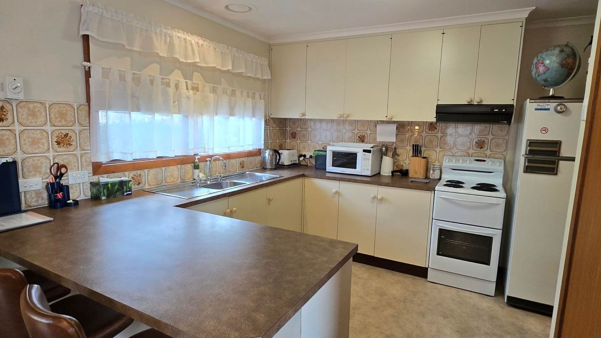 A kitchen with a central island, a microwave, an oven, and a stove.