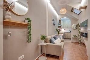 Ein modernes Interieur mit einer Couch, einem kleinen Beistelltisch, einem Spiegel und einer Pendelleuchte.