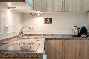 A modern kitchen with a stainless steel sink, wooden cabinets, a granite countertop, and a coffee maker. - Cozy and lovely apartment located in the historic center of Málaga. (Málaga)