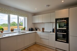Eine moderne Küche mit eingebautem Backofen, Spüle und einem Fenster mit Blick auf Grünflächen.