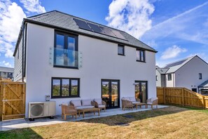 A two-story house with a flat roof, large windows, and a covered patio area with outdoor furniture. - Tir Ha Mor (Upton)