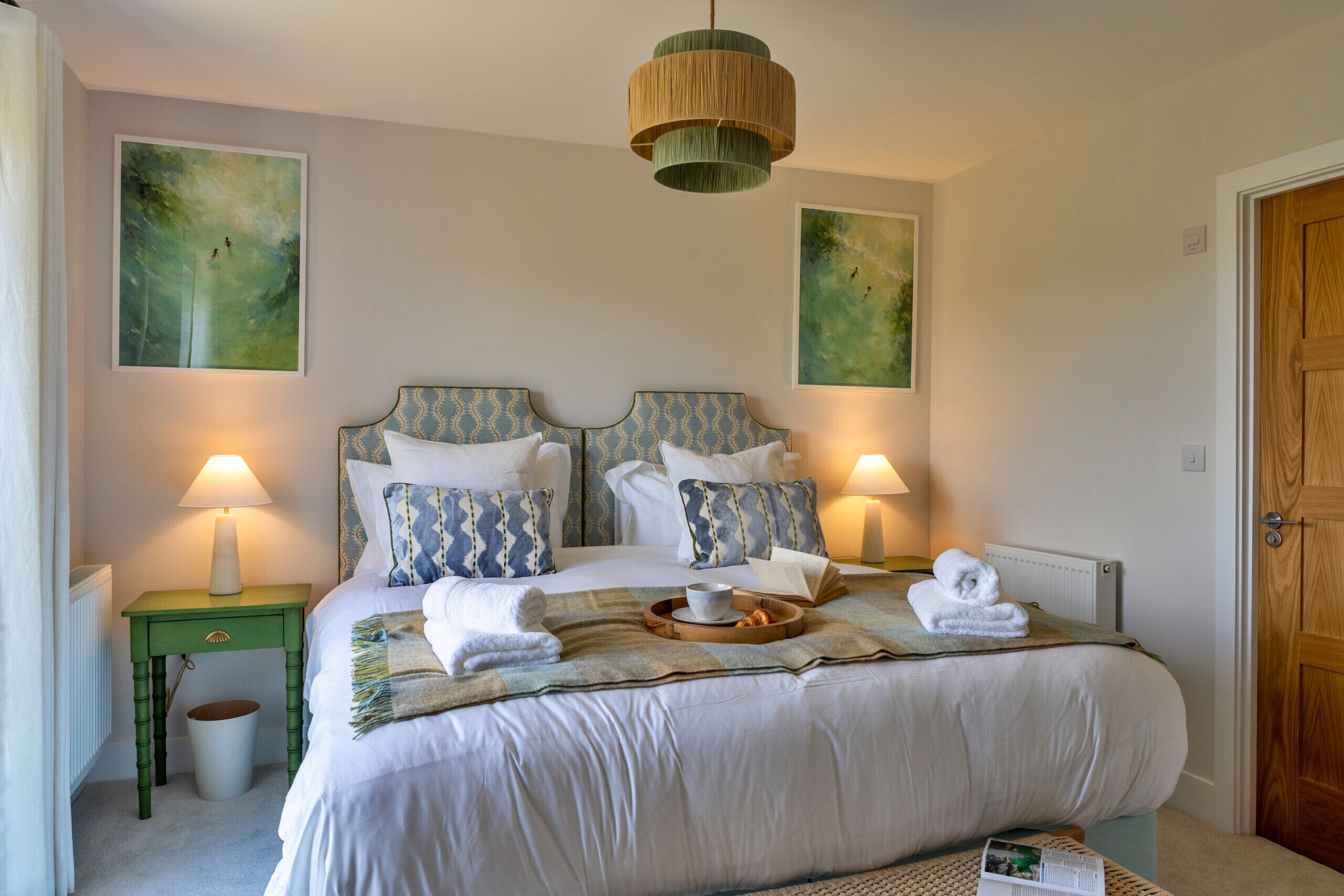 A neatly arranged bedroom with a bed, two bedside lamps, a bedside table, and a door.