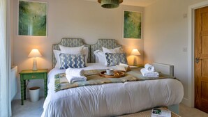 Une chambre à coucher bien rangée, avec un lit, deux lampes de chevet, une table de chevet et une porte.