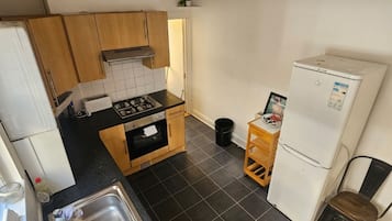 Eine kleine Küche mit Herd, Spüle und Kühlschrank.