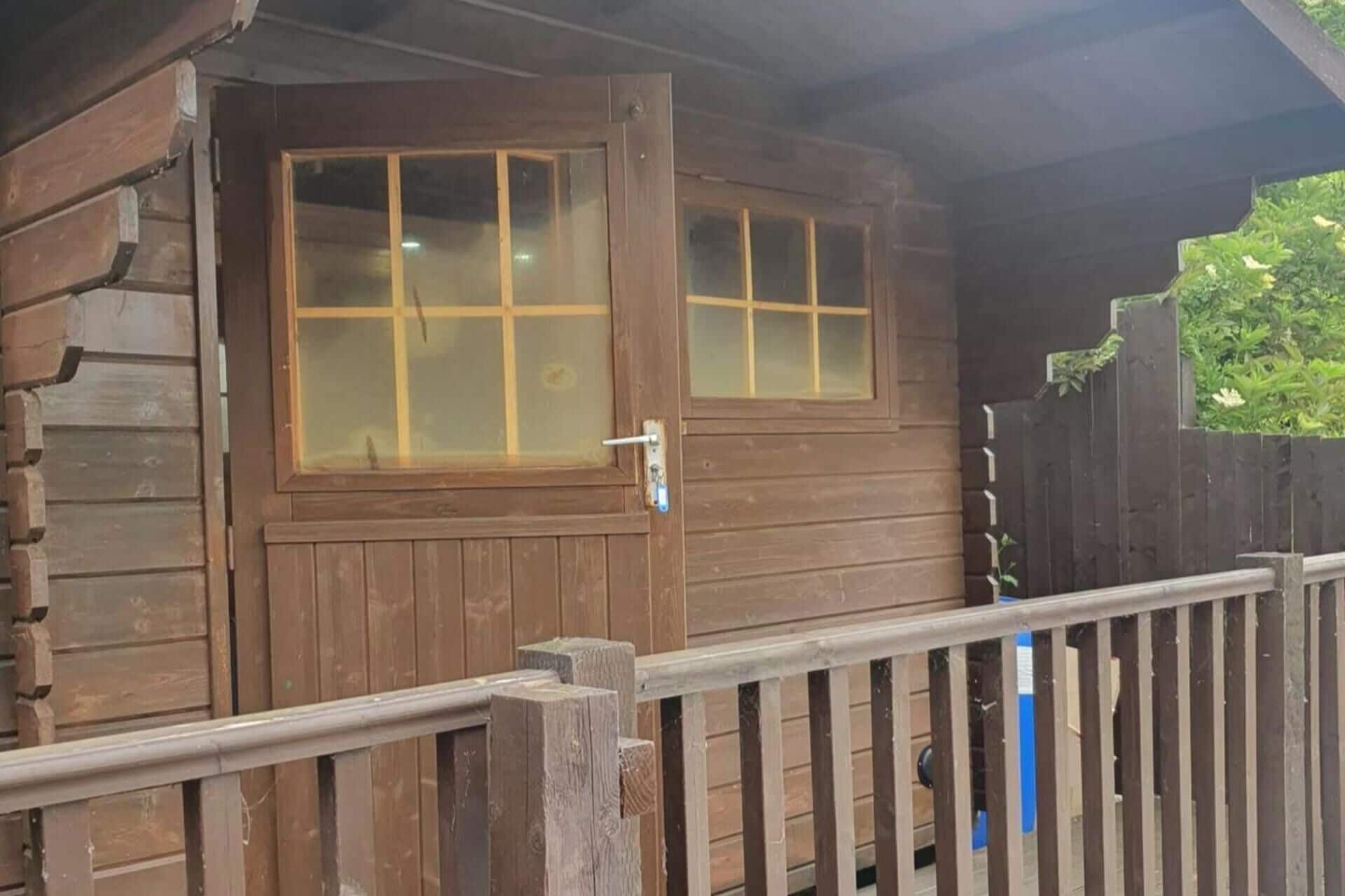 A wooden cabin with a glass door and a metal railing.