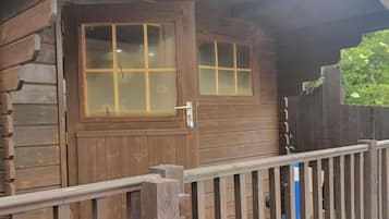 A wooden cabin with a glass door and a metal railing.