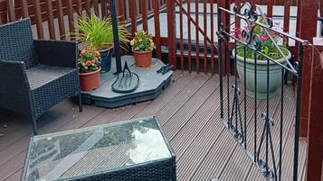 A deck with outdoor furniture, potted plants, and a metal gate.
