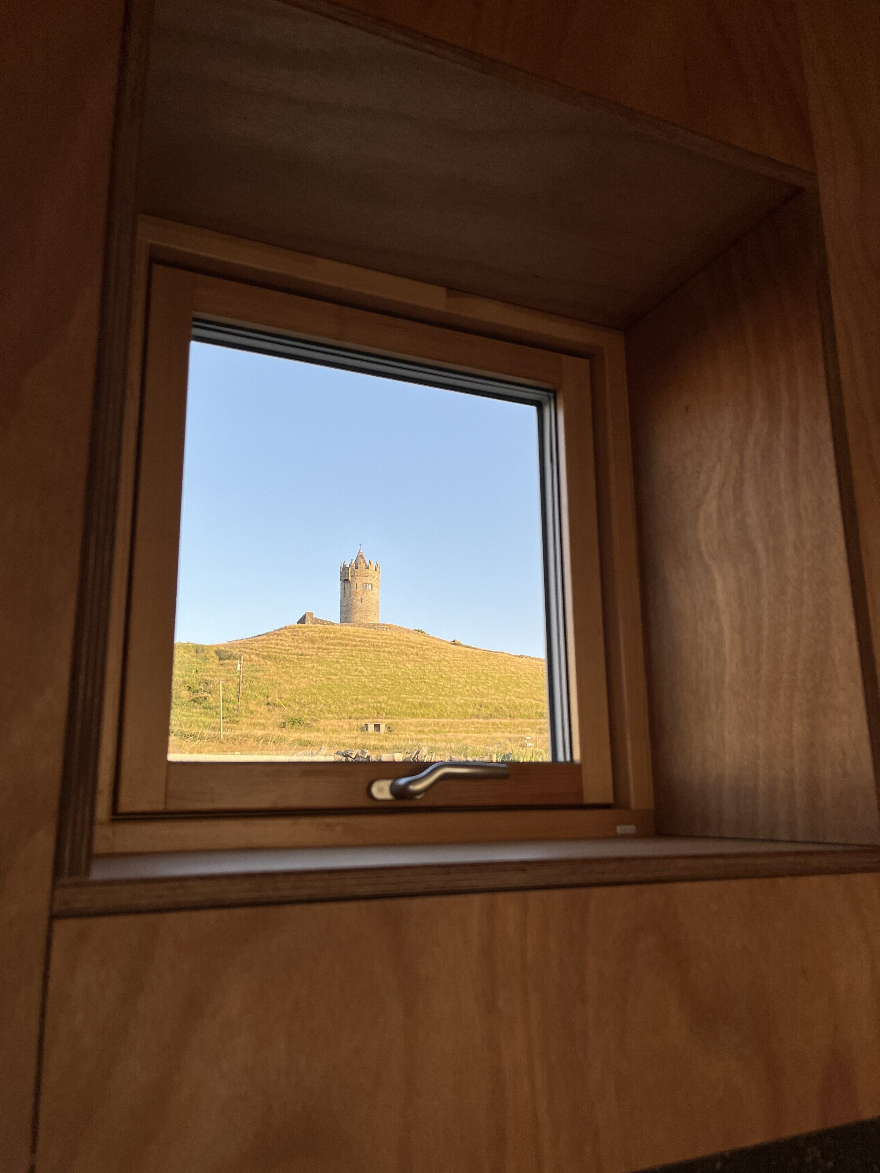 Ein Fenster mit Blick auf einen Hügel und einen Turm.