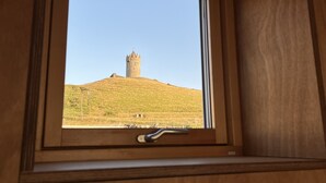 A window with a view of a hill and a tower.
