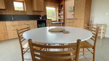 A modern kitchen with wooden cabinetry, a round dining table, and a pendant light.