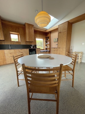 Una cocina moderna con armarios de madera, una mesa redonda de comedor y una lámpara colgante.