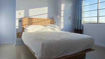 A modern bedroom with a wooden bed, a nightstand, a wall-mounted lamp, and a window with curtains.