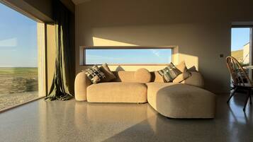 A modern living room with a large window, a sofa, and a chair.