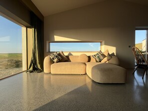 A modern living room with a large window, a sofa, and a chair.