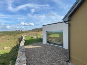 A modern building with a stone wall and gravel pathway leading to a large window.
