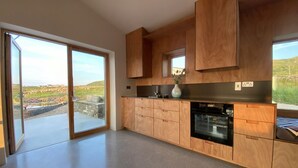 A modern kitchen with wooden cabinets, a built-in oven, and a large sliding glass door leading to an outdoor area.