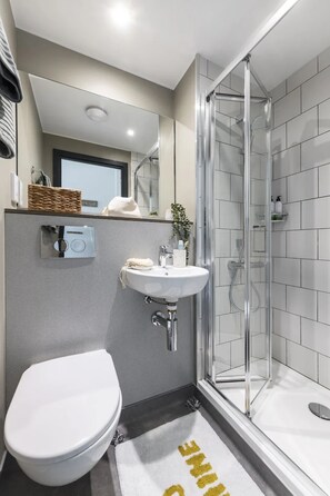 Ein modernes Badezimmer mit Toilette, Waschbecken und einer Duschkabine.