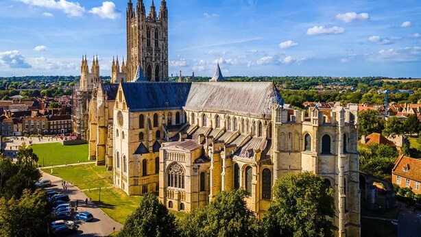 A historic cathedral with a prominent tower, surrounded by a green park and a parking area. - Student Only Riverside (Canterbury)