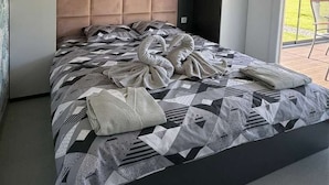 Un dormitori modern amb un llit gran, un reposacapses amb fons amb fetre i una làmpada al sostre.