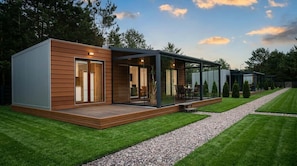 A modern house with a wooden exterior, a glass-enclosed porch, and a gravel pathway.