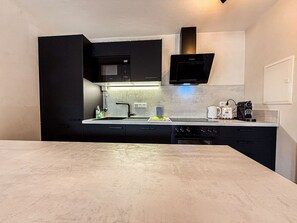 A compact kitchen with a built-in microwave, a coffee machine, and a sink. - ArgenZeit Vacation Rental – Centrally Located in Oberstaufen (Oberstaufen)