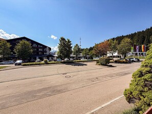 A parking lot with cars, a building with a sign, and trees. - ArgenZeit Vacation Rental – Centrally Located in Oberstaufen (Oberstaufen)