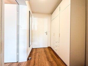 A hallway with a wooden floor, white walls, and a white door. - ArgenZeit Vacation Rental – Centrally Located in Oberstaufen (Oberstaufen)