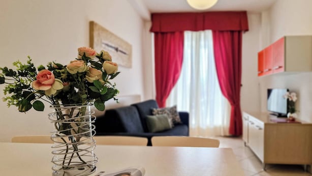 Een woonkamer met een bank, een eettafel met een bloevas en een tijdschrift.