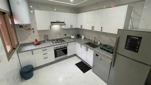 A modern kitchen with white cabinets, a built-in oven, a dishwasher, and a refrigerator. - Modern Stay City Center with Balcony (Marrakech)