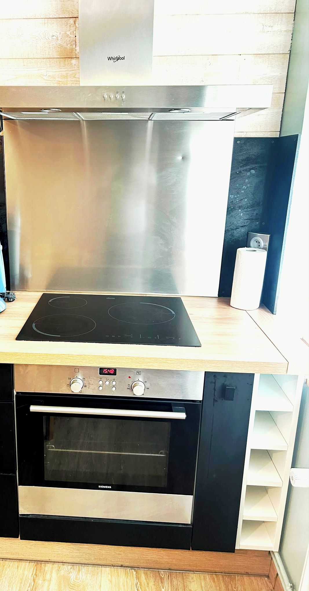 Une cuisine équipée d’une hotte en acier inoxydable, d’une plaque de cuisson à induction noire et d’un four encastré.