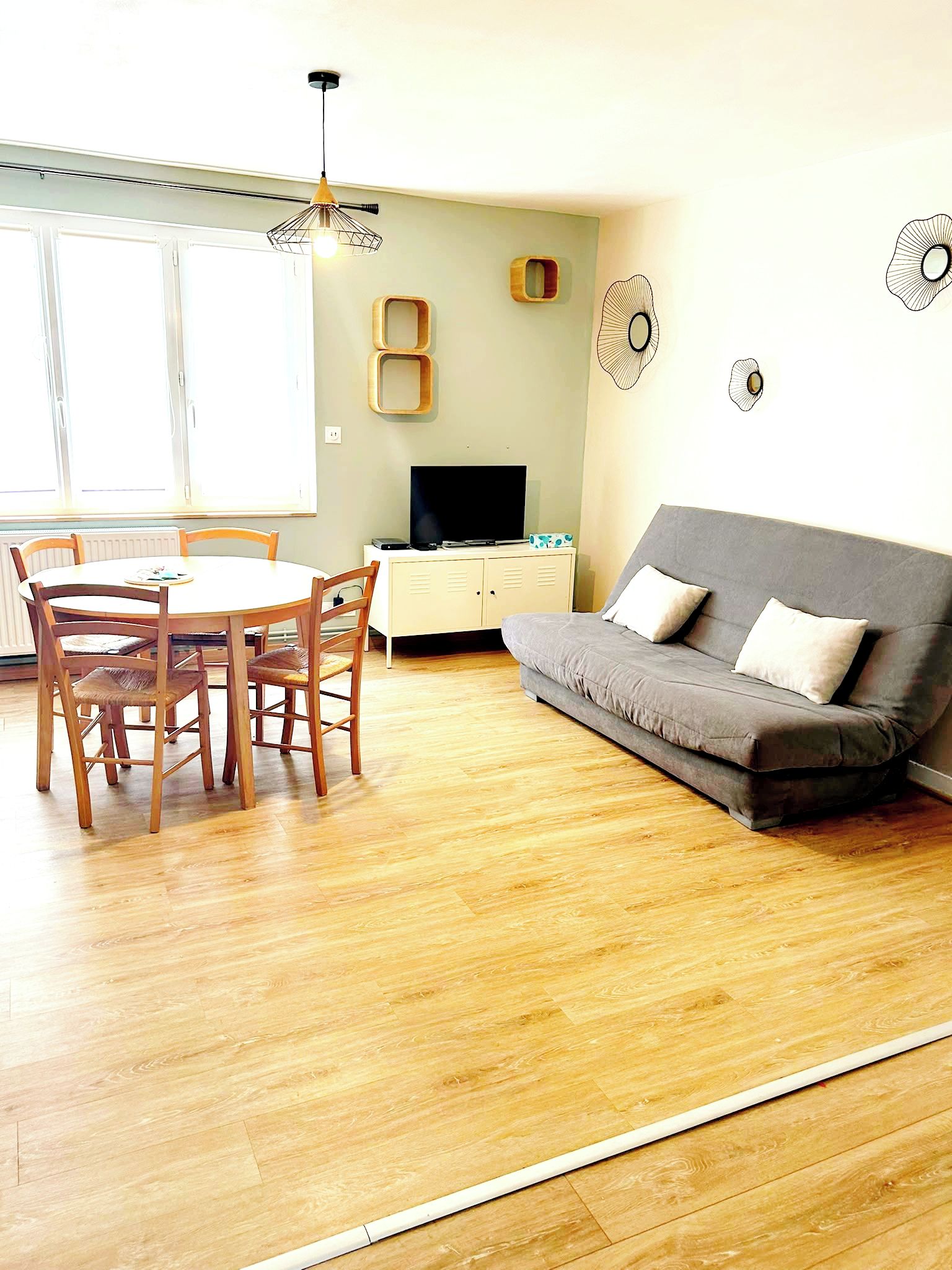 Een woonkamer met een eettafel, stoelen, een bank en een televisie.