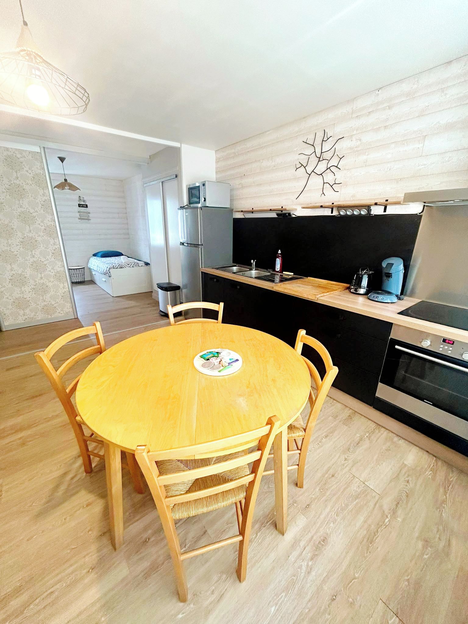 A compact kitchen with a dining table, chairs, and a microwave on the counter.