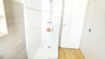 Une salle de bain moderne avec une douche à parois de verre, un lavabo blanc et un plancher en bois.