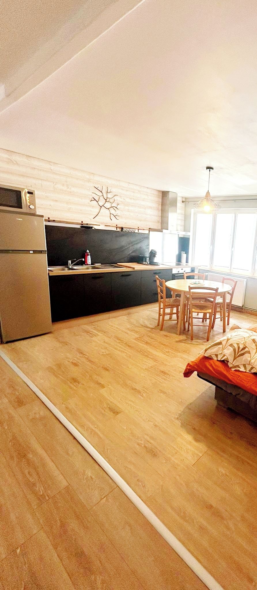 A modern kitchen with a built-in oven, a dining area with a table and chairs, and a wooden floor.