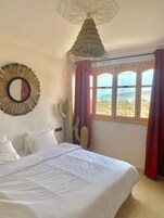 Un dormitorio con cama, ventana grande y una decoración de cactus.